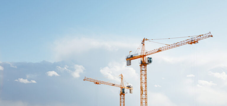 building cranes at the construction site on blue sky background